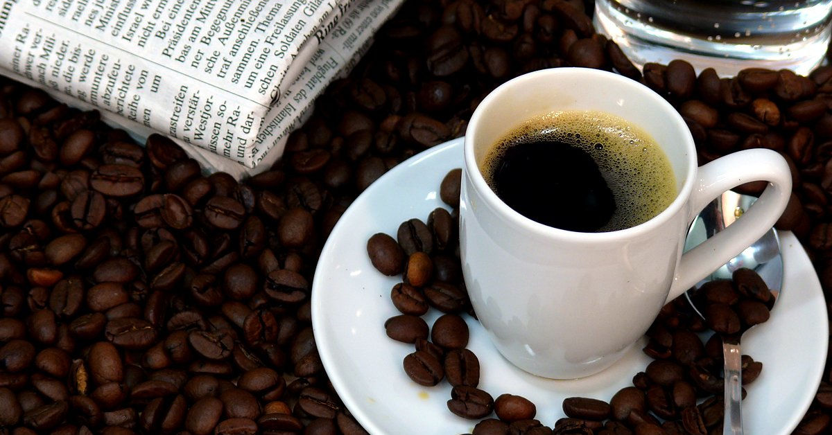 Coffee beans, newspaper and a cup of coffee